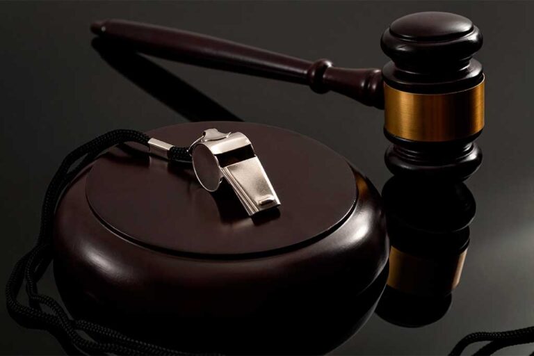 Metal whistle and wooden judge gavel on dark background
