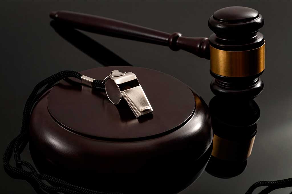 Metal whistle and wooden judge gavel on dark background