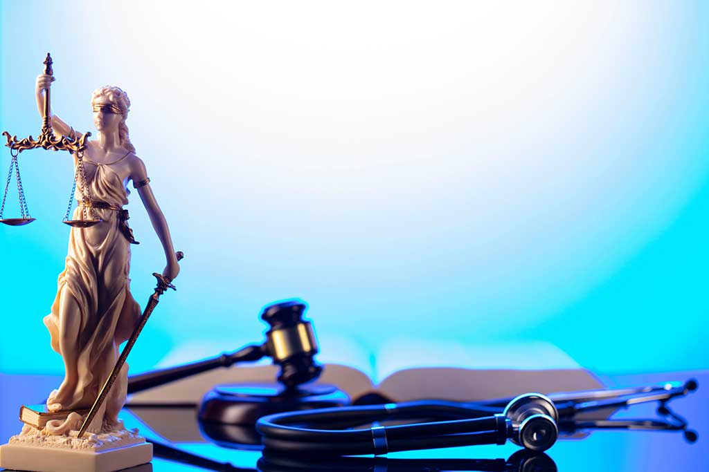 Gavel, legal code and stethoscope on the glass table