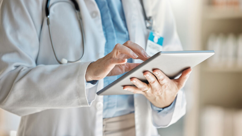 Out-of-network medical provider reviewing insurance claim on tablet.